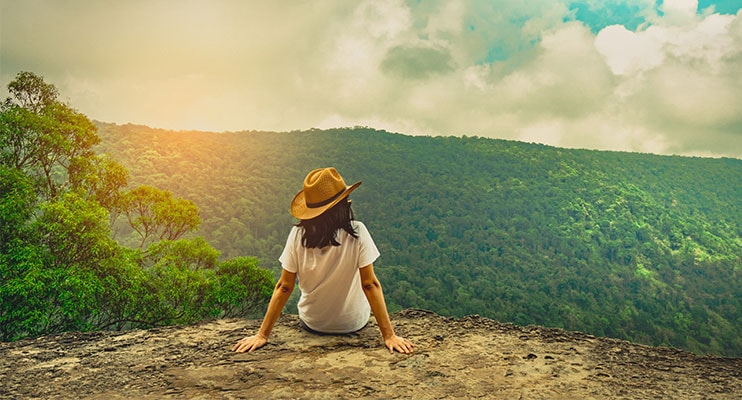 Woman Sitting On A Cliff Over Looking A Mountainous Terrain